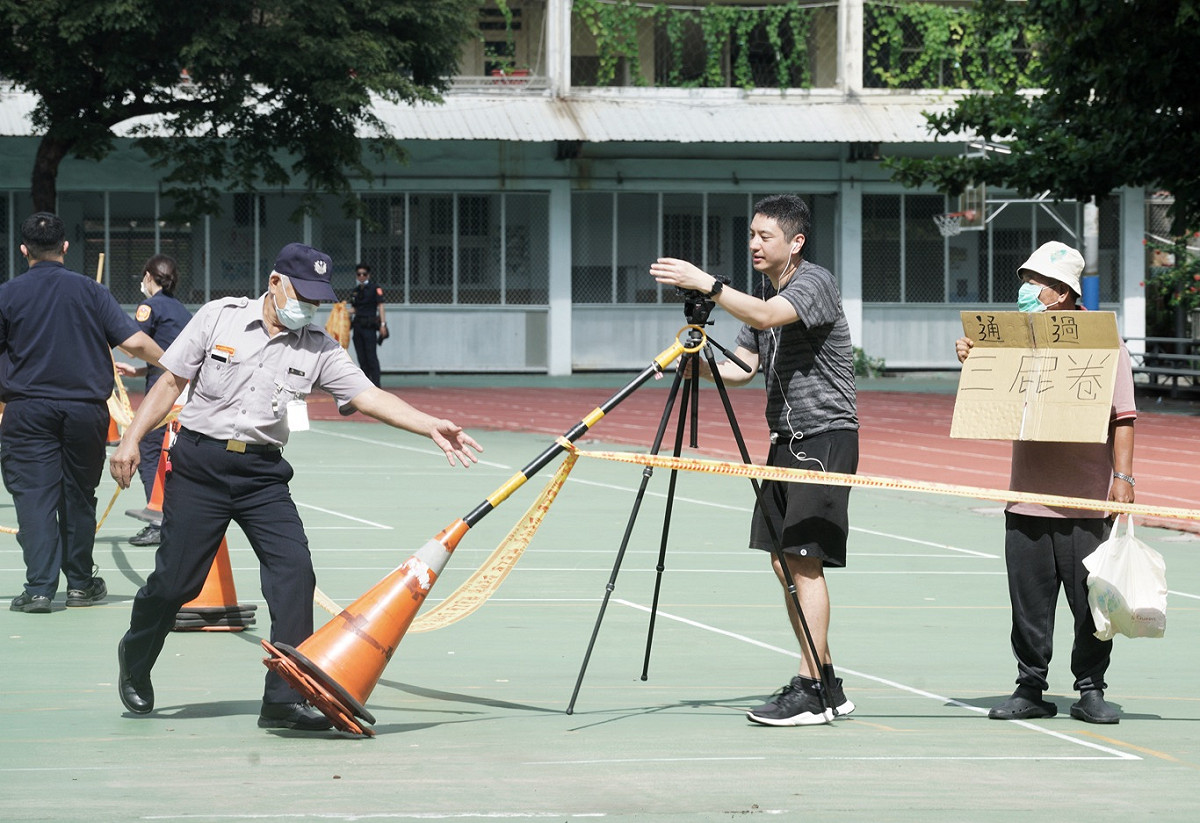 選務人員原先架設的警戒線離投票所僅15公尺，經重新測量後，將進行錄影的民眾勸離到30公尺外。 圖：張良一/攝