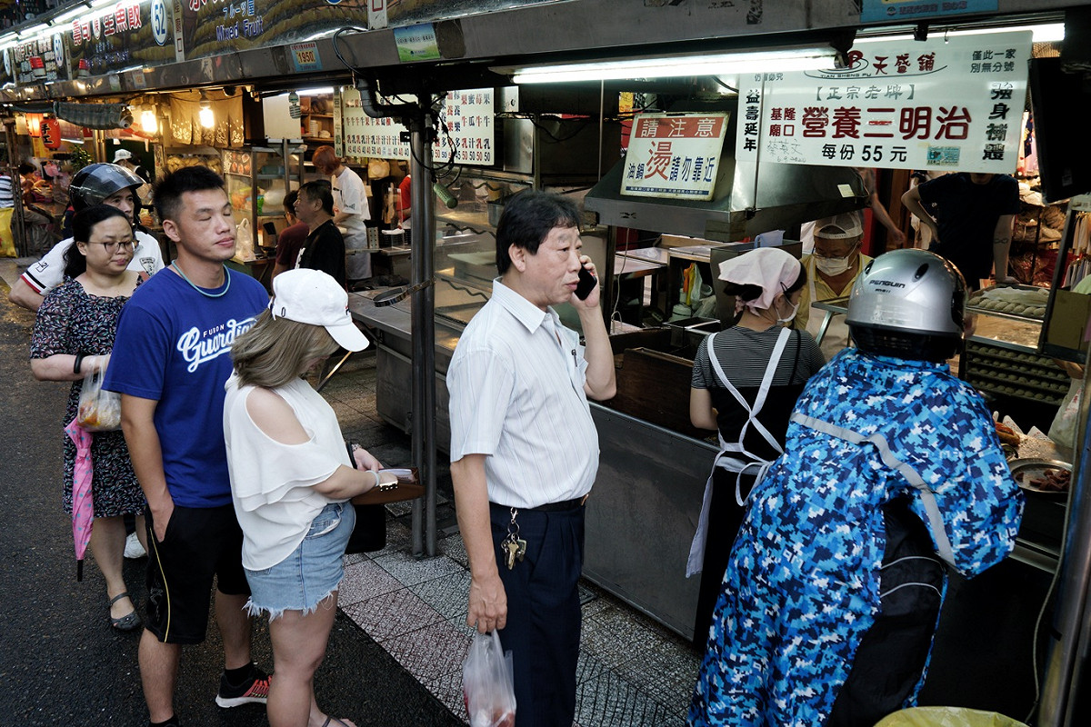 遊客在廟口夜市的營養三明治攤子前排隊購買。 圖：張良一/攝