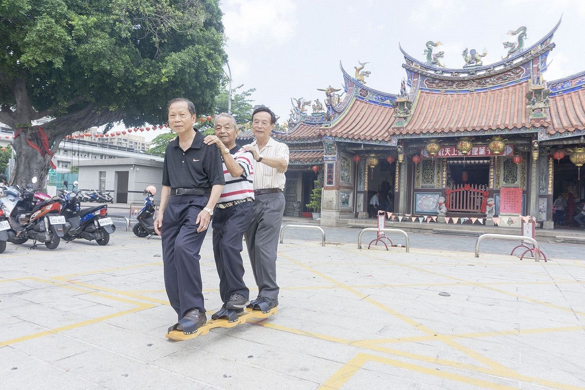 端午民俗活動，萬和宮董事長等體驗親子競賽的三人木屐。 萬和宮/提供