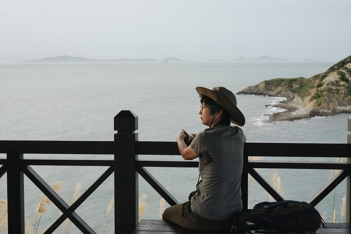 下班後的Jen獨自一人在馬祖東莒的47據點旁的涼亭眺望晚霞。無需費心神與人說話，一個人沈浸在美麗的晚霞之中，她很珍惜來馬祖當志工，可以跳脫家庭日常生活的繁瑣，獨享東莒海天一色的遼闊與靜謐，心情放鬆，很是享受。 圖：張良一/攝