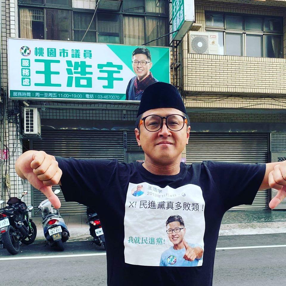 台灣新住民代表人物之一的何景榮，穿著印有印有王浩宇肖像的T恤，在王浩宇服務處前比出倒讚手勢，高喊新住民站出來。 圖：翻攝自老師雞 何景榮臉書