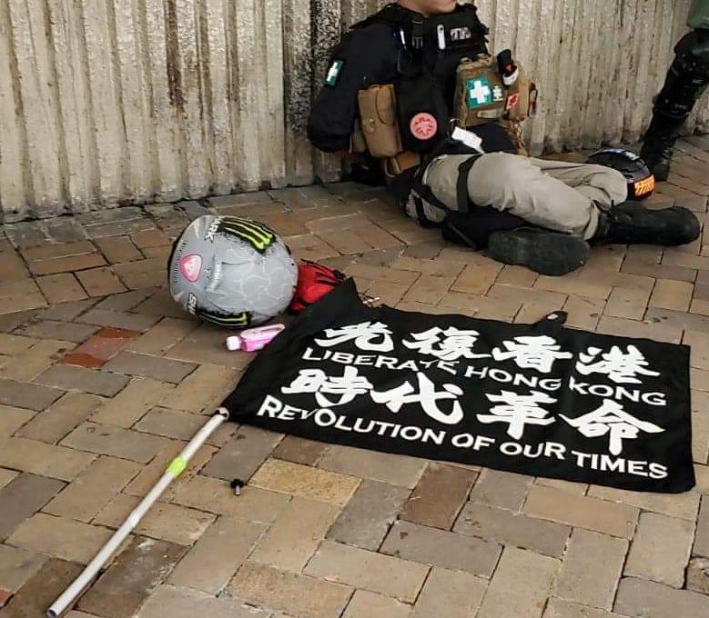 香港示威者坐在地上，前方有「光復香港，時代革命」旗幟。 圖：翻攝自香港警察臉書