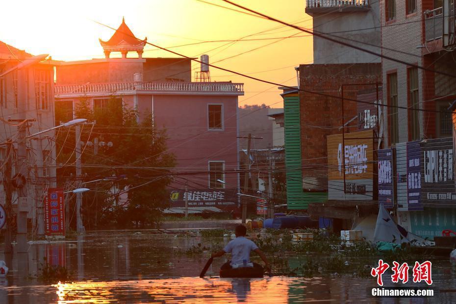 中國境內連日暴雨，造成鄱陽湖周遭住戶房屋淹沒。居民在街道上划著橡皮艇出門。 圖：中新網