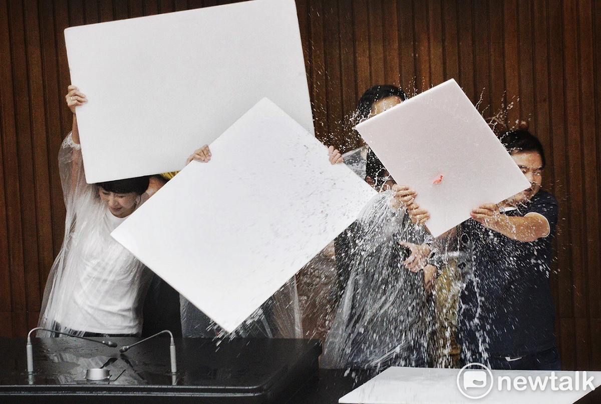 國民黨立委在監察院人事案開票時向主席台丟擲大量水球，民進黨立委則高舉白色板子擋水球。 圖：張良一／攝