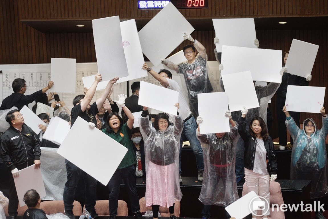 國民黨立委在監察院人事案開票時丟擲大量水球，民進黨立委則高舉白色板子擋水球。 圖：張良一／攝