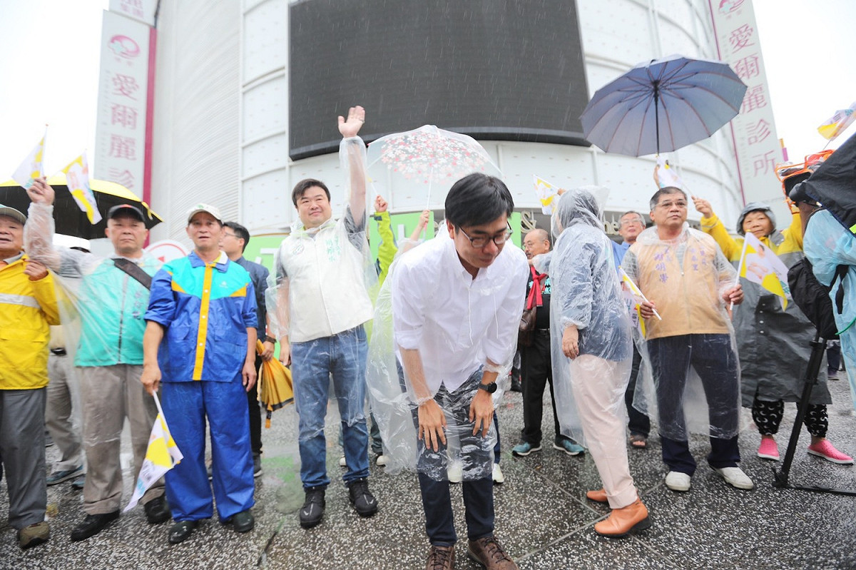 陳其邁(中)冒雨在路口鞠躬拜票。 圖：陳其邁競辦/提供