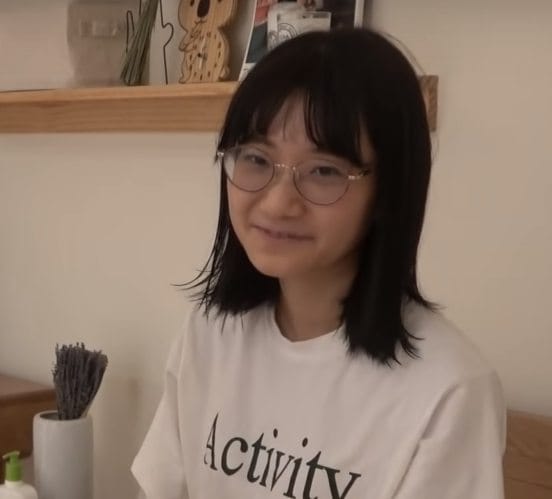 愛莉莎莎戴著圓框眼鏡與及肩的半長髮，非常像學生。 圖：翻攝YouTube