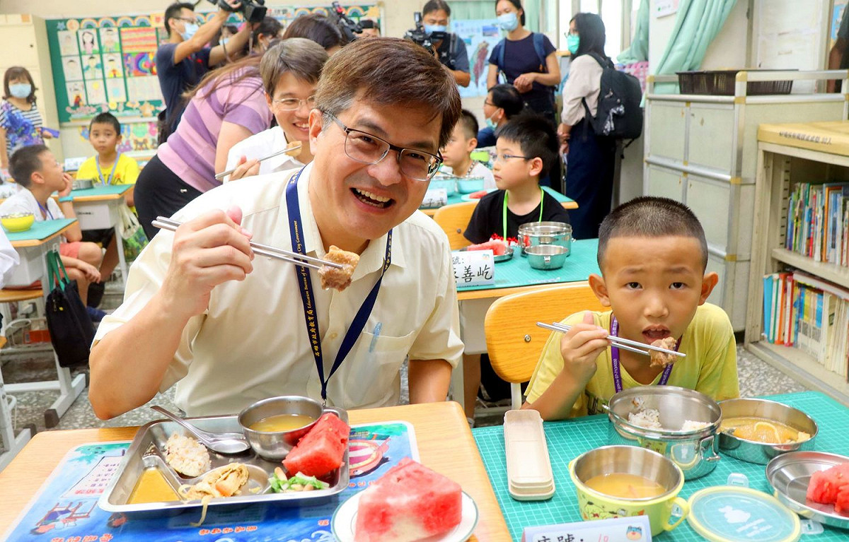 高市教育局長謝文斌(左)與學童共用營養午餐。 圖：高雄市政府/提供