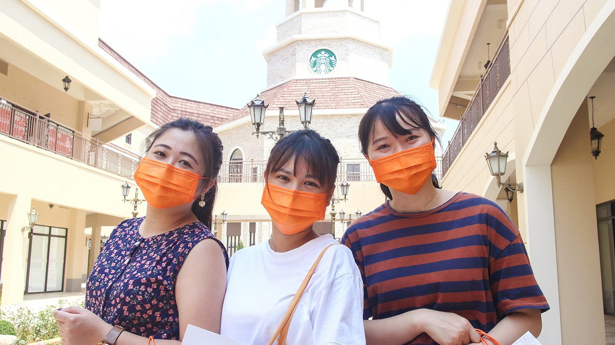 戴帶著愛馬仕橘口罩與星巴克鐘樓拍美照。 圖：麗寶Outlet Mall／提供