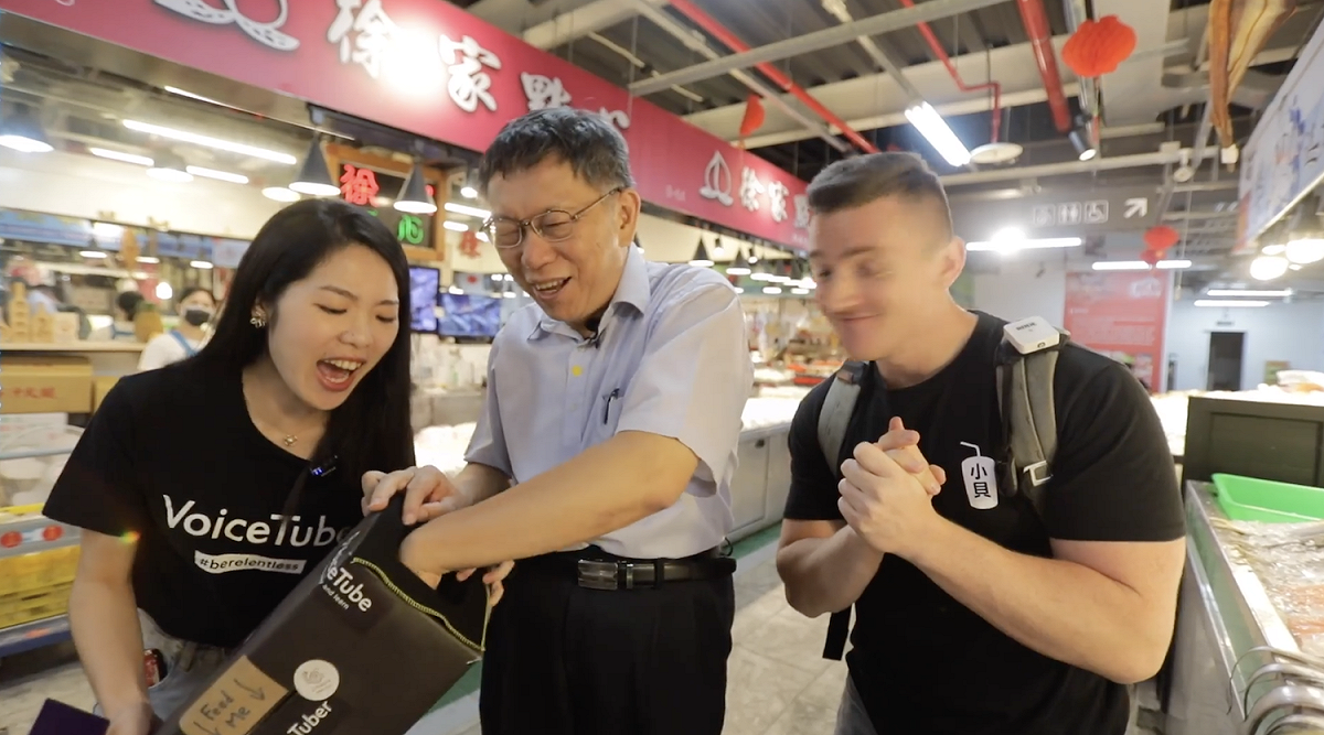 台北市長柯文哲合體網紅「LoganDBeck」小貝及「VoiceTube看影片學英語」Elena前往南門中繼市場，挑戰用英語買菜。 圖：翻攝影片