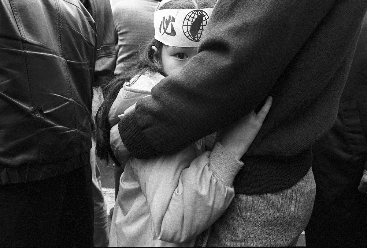 1989年12月，中山堂內國民大會舉行集會，場外民主阿草們抗議萬民國會老法統，一位小女孩依偎在父親的懷裡張望。 圖：杭大鵬／攝