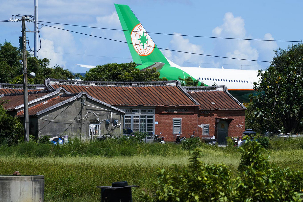 一棟靠近桃園機場的傳統民宅，和機場內一架長榮航空的尾翼，形成強烈對比。由於此地位在桃園航空城計畫案中的第三跑道預定地，土地徵收啟動後，此地居民將被迫遷出他們長久生活與工作的土地。 圖：張良一/攝