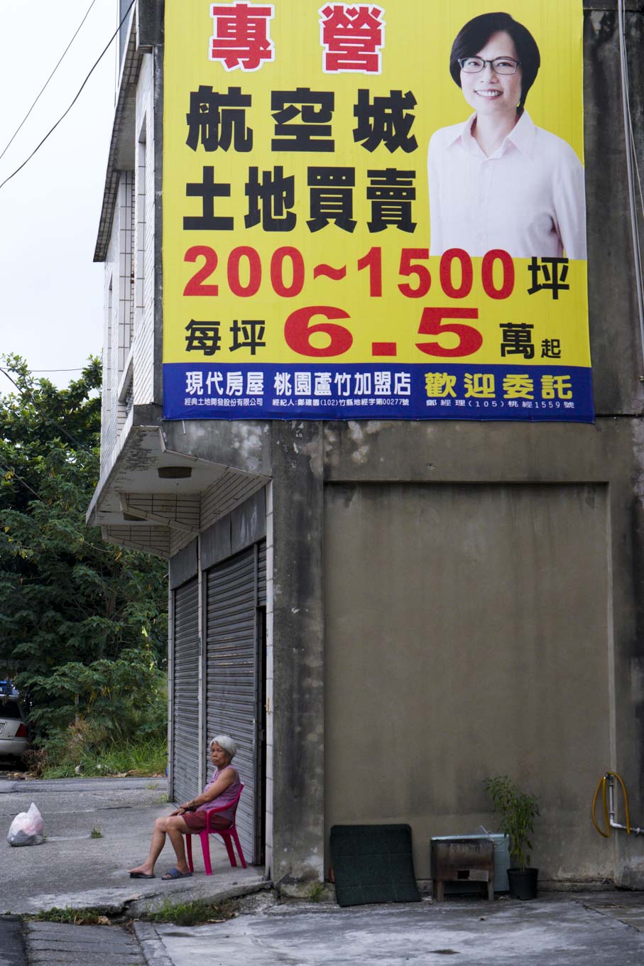 一面大型的航空城土地買賣廣告招牌張貼在桃園大園的一棟民宅上，由於大園位在桃園機場第三跑道預定地的蛋黃區內，航空城計畫案徵收啟動後，此地近萬居民將全數面臨被迫遷移搬離，離開長久居住的土地和家園。 圖：張良一/攝