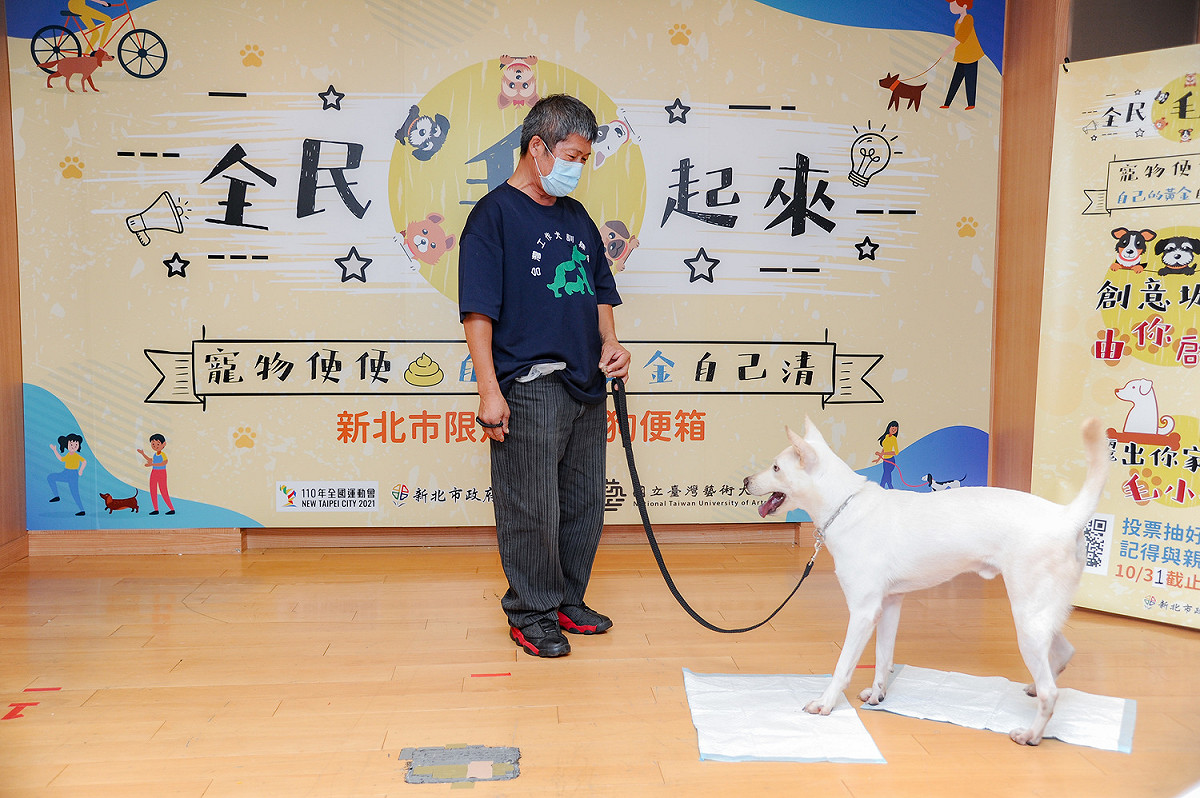 台灣工作犬訓練學校負責人陳懷櫻、訓狗教練顧乾立及狗狗姆咪帶來訓練犬隻如廁表演。  圖：新北市環保局／提供