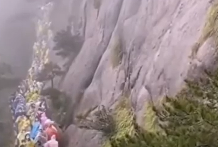中國遊客趁著國慶、中秋雙節小長假赴安徽黃山景區遊玩，然而，從遊客側拍的影片中可見，熱門景點塞滿了遊客，再加上風風雨雨的天氣，讓整個隊伍行進更慢、更長 圖：翻攝自環球時報