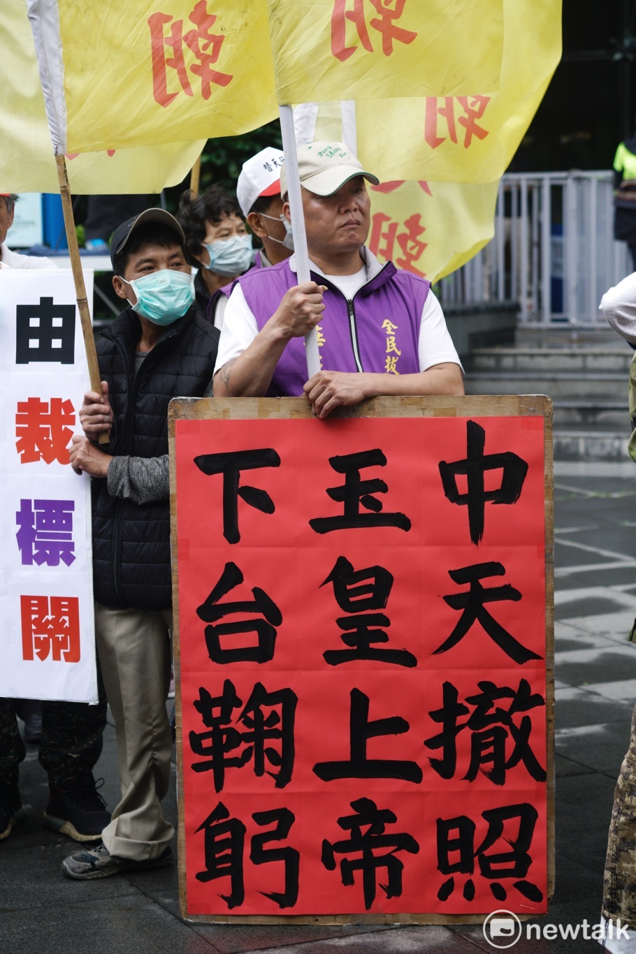 一位抗議民眾在現場拿著「中天撤照 玉皇大帝 下台鞠躬」標語。 圖：張良一/攝