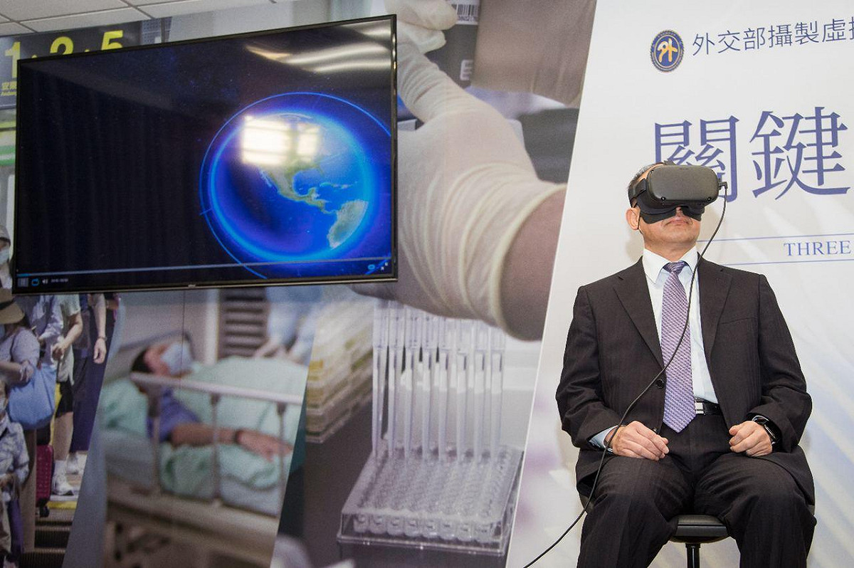 與會者可透過電視螢幕同步觀看曾厚仁體驗的VR畫面。 圖：外交部提供