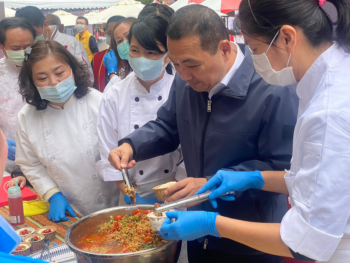 侯友宜巡視成果展攤位，品嚐打拋豬口味的窩窩頭。  圖：新北市勞工局提供
