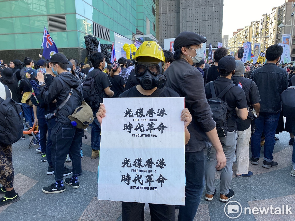 遊行民眾打扮成港人抗爭模樣，高舉「光復香港，時代革命」標語。 圖：周煊惠／攝