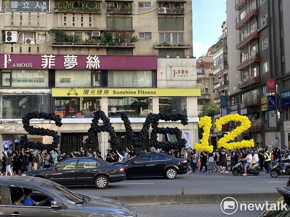 遊行隊伍高舉「SAVE 12」。 圖：周煊惠／攝