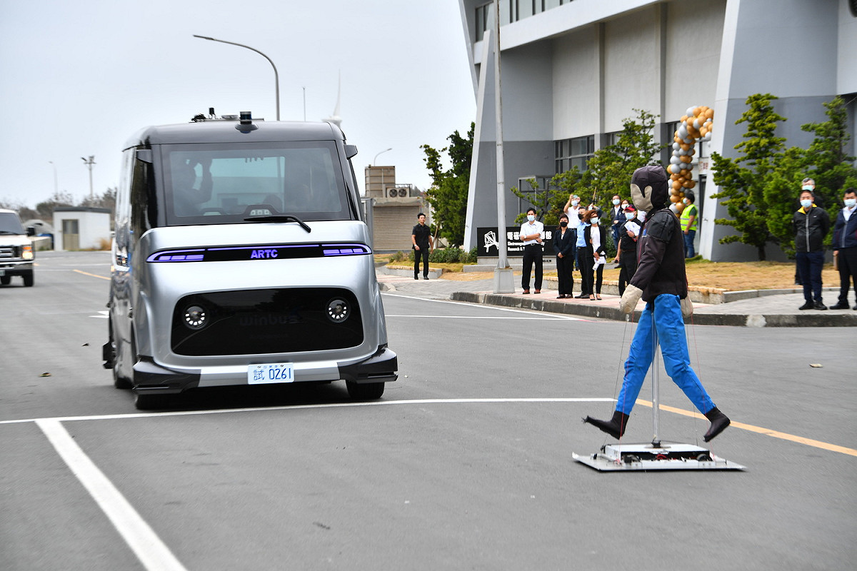 假人模擬行人突然闖進車道，測試第一輛國人自研自製的自駕無人小巴WinBus感應突入的煞車效能。 圖：行政院提供