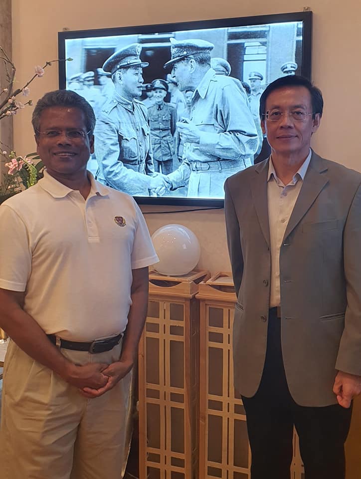 曾經擔任美國外交官的孟迪斯（左）在臉書po出訪問台北期間，曾在電視影片「遇見」麥克阿瑟將軍（螢幕中右）。 圖：翻攝自孟迪斯臉書