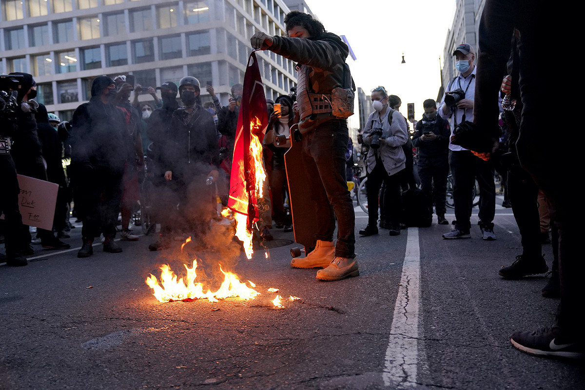 川普支持者及反對者爆發多起衝突，圖為川普反對者焚燒支持者的紅色旗幟。 圖：達志影像／美聯社