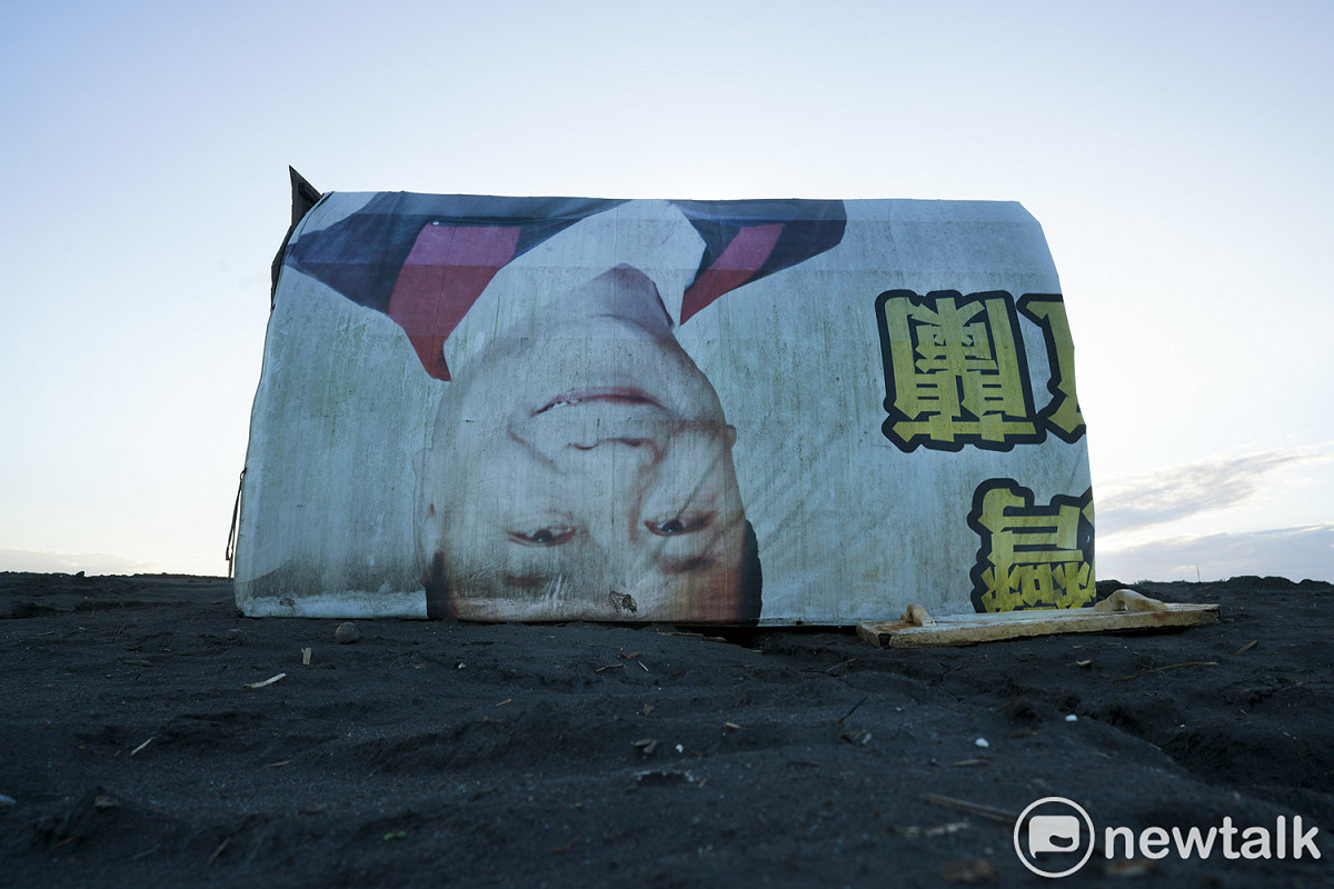 一張競選帆布廣告被扒鰻苗人拿來當作遮風避雨的魚寮。 圖：張良一/攝