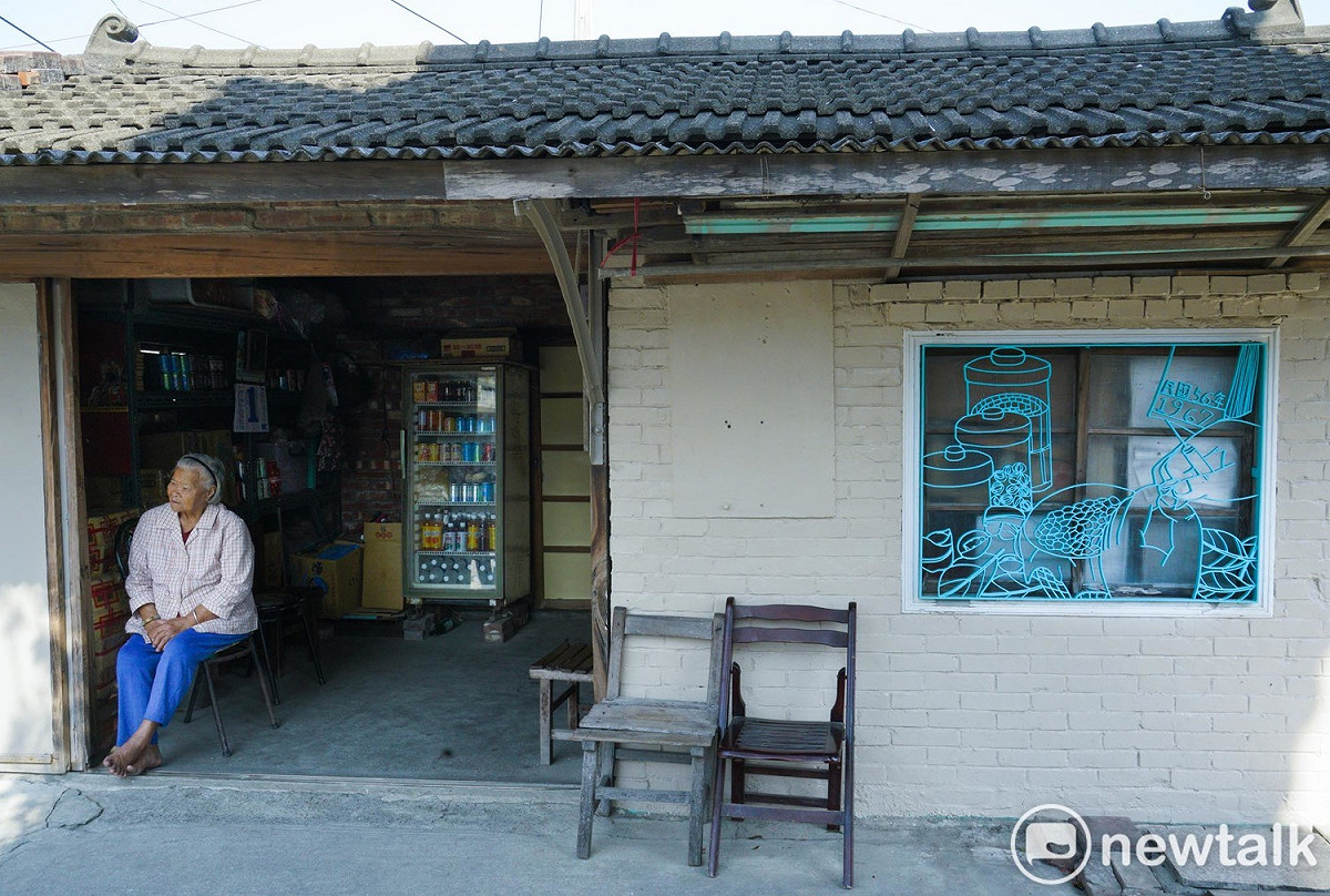 92歲的柑仔店老闆娘李林選阿嬤坐在柑仔店的門口，負責椬梧城鎮之心人文景觀再造計畫的團隊透過訪談，將她和柑仔店故事呈現在柑仔店的窗花上。柑仔店位在廟埕旁，是許多參拜民眾購買茶水、短暫休憩的好所在，阿嬤也經常與他們熱絡互動。 圖：張良一/攝