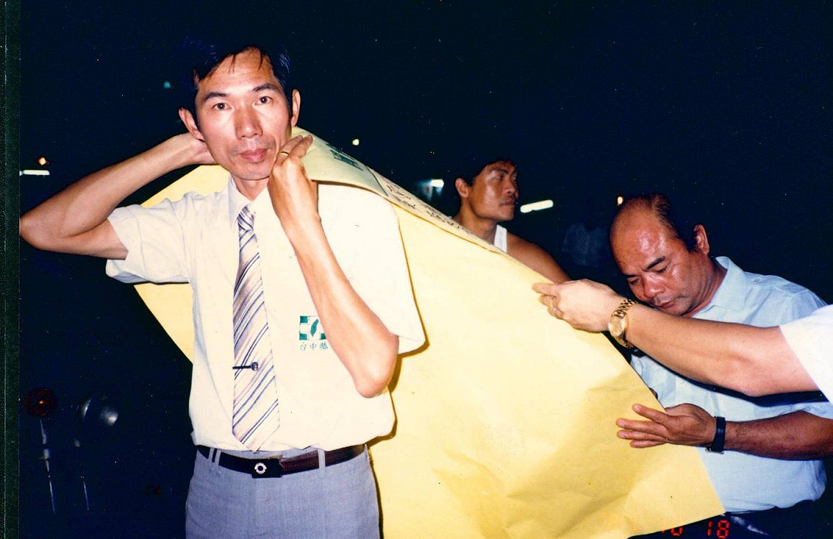 圖是1988年，羅隆錚老師推動「國會全面改選」時，揹著海報在街頭讓民眾簽名支持。 圖／黃世殿提供
