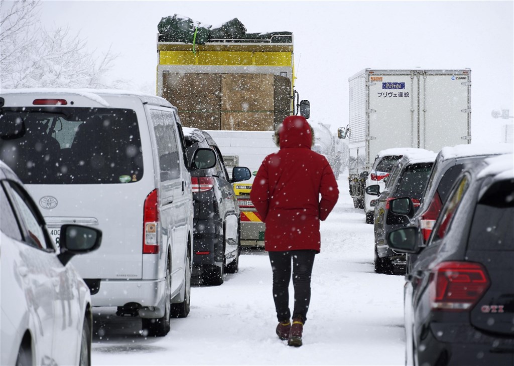 日本受強烈冷氣團影響，新潟縣、群馬縣降雪量破紀錄，境內高速公路16日晚間起交通阻塞，17日上午約1000輛車卡在積雪中動彈不得，車陣最長蔓延16.5公里。圖為民眾行走在高速公路「關越自動車道」車陣之間。 圖：共同社／中央社提供