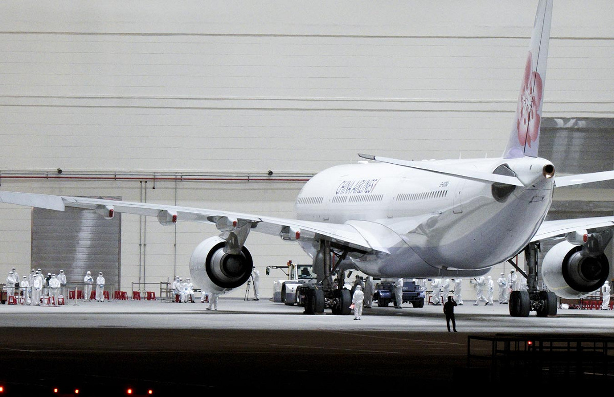 第二批武漢返台包機返抵桃園機場後，飛機被指引到維修機棚，由在場等候的檢疫人員為169位旅客、12位機組員及10位隨機醫護人員進行檢疫分組。 圖：張良一/攝
