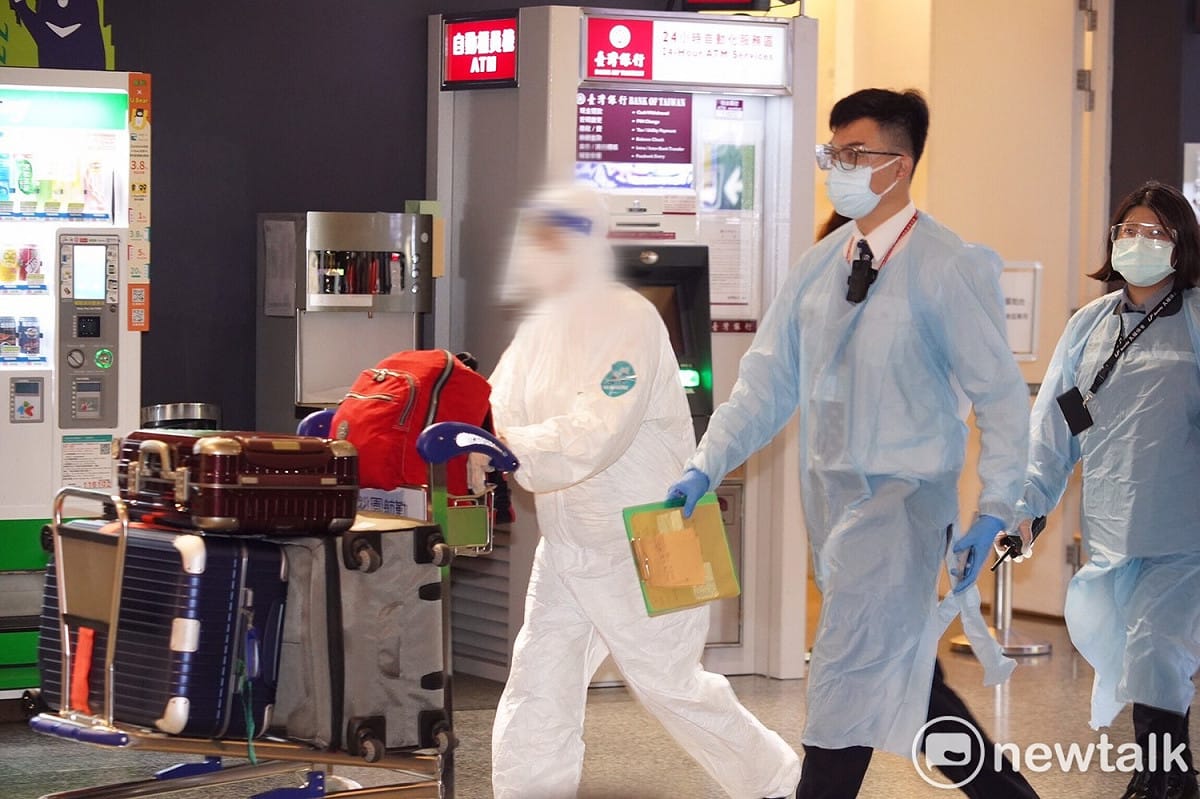 英國返台旅客穿戴全副防疫裝備步出海關，由機場檢疫人員陪同前往搭乘防疫專車。 圖：林昀真/攝（資料照）