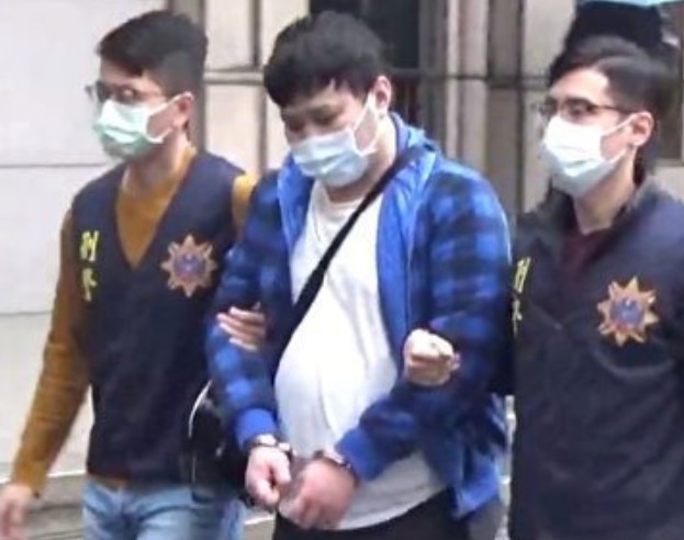 洪姓男子被上銬移送時低頭不發一語，應訊時也否認PO文恐嚇。 圖：刑事局提供