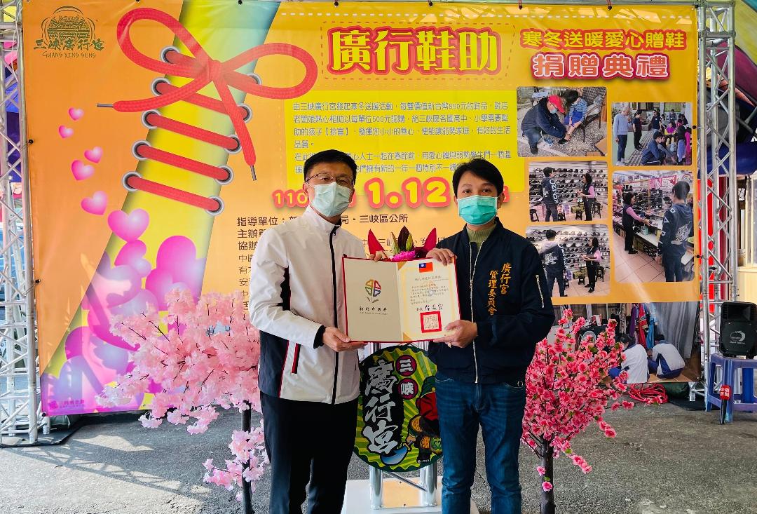 三峽廣行宮寒冬送暖，教育局長張明文 (左)代市長侯友宜頒感謝狀給廣行宮主委黃騰霆。  圖：新北市教育局提供