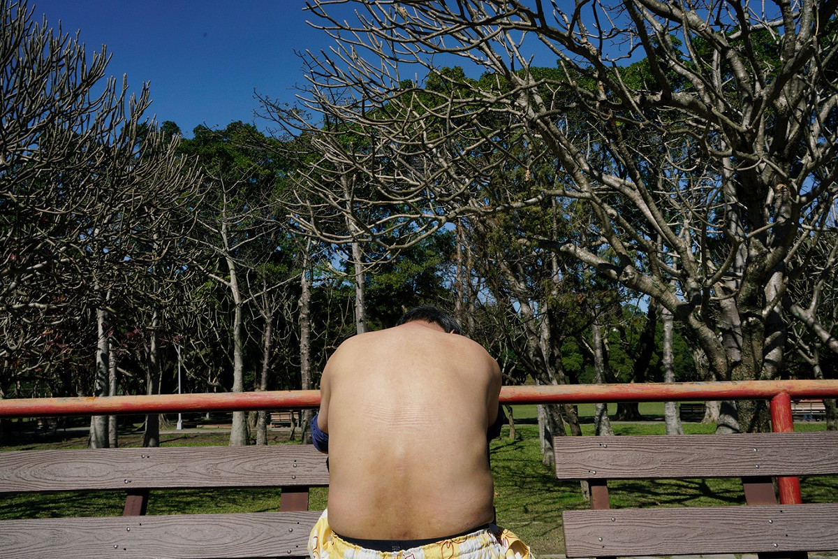 一位民眾脫掉上衣，讓溫暖的陽光將全身曬得通體舒暢。 圖：張良一/攝