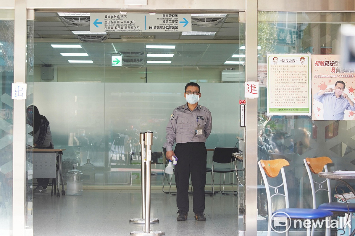 桃市衛生局今正常運作，工作人員在門口為民眾量體溫，噴酒精。 圖：林昀真/攝