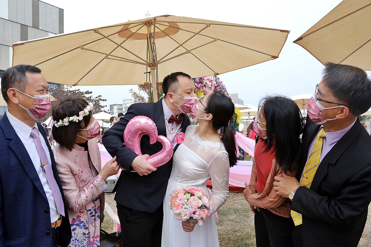 嘉義市舉行集團結婚，因疫情關係，新人戴著口罩接吻。 圖：嘉義市政府/提供