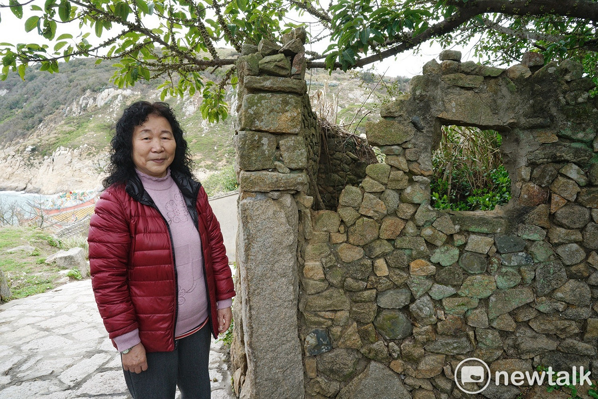 劉美珍在她的老家前合影。劉美珍說，她身旁的石頭屋是她公公的房間，當時她和先生、公公和五個孩子就擠在小小的屋子生活。她們後來舉家遷往台灣，近年看她的好姐妹王明恩的女兒把老家改建作民宿作得有聲有色，也興起了改建老家的念頭。 圖：張良一/攝