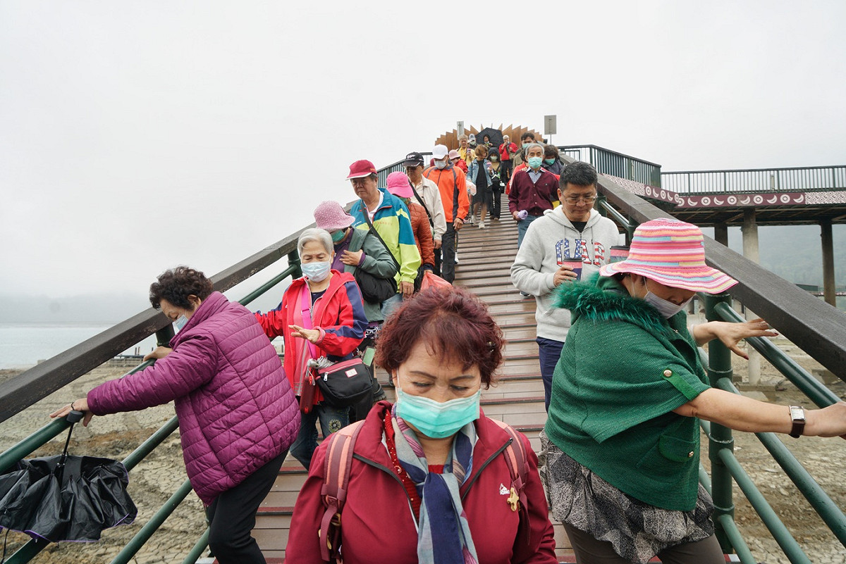 到日月潭觀光的遊客雙手抓著引橋的欄杆一步一步走去登船。 圖：張良一/攝