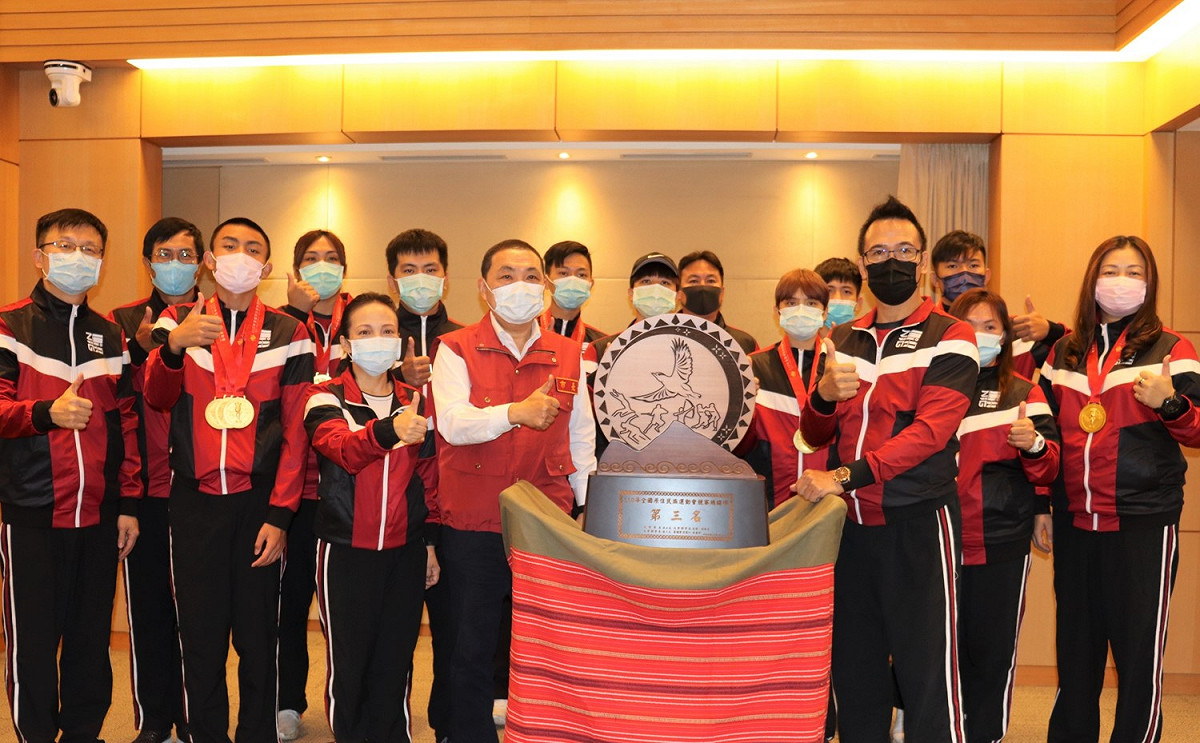 侯友宜 (左七)、原民局長羅美菁 (左四)、教育局長張明文 ( 左一)、林慶勝總教練 (右三)率領新北代表隊金牌團隊向侯友宜獻獎。 圖：新北市原民局提供