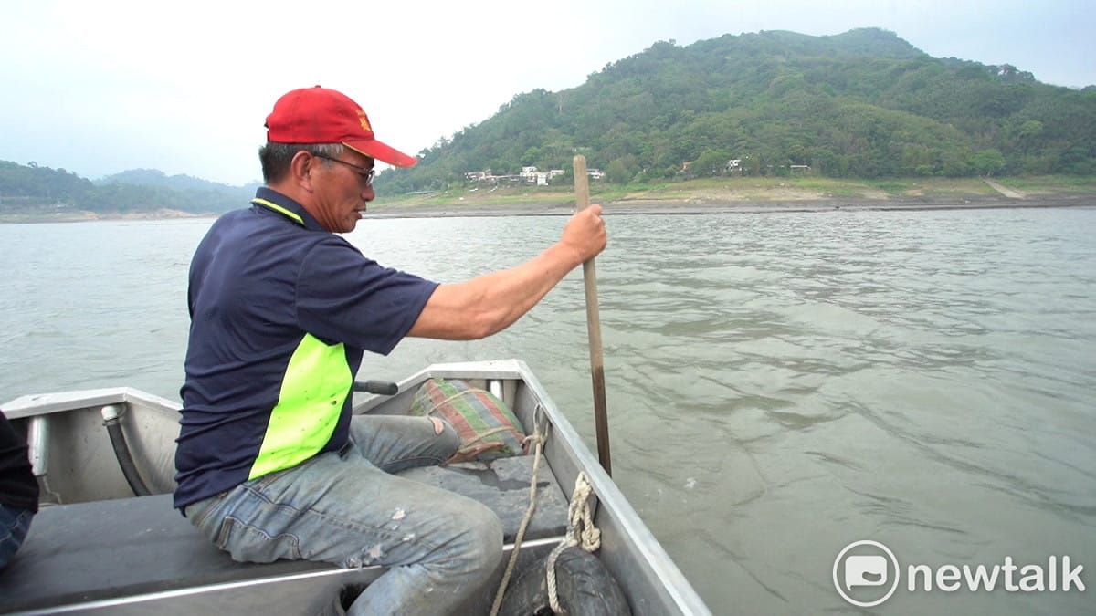 呂學賢拿著長約1.5公尺的木槳插入石門水庫水中，許多地方水深僅有1.2公尺，靠近薑母島臨時碼頭的水域淤積更為嚴重，水深甚至不到1公尺。 圖：林昀真／攝