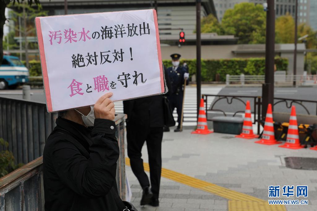 日本民眾舉牌反對核廢水入海。 圖：翻攝自新華社