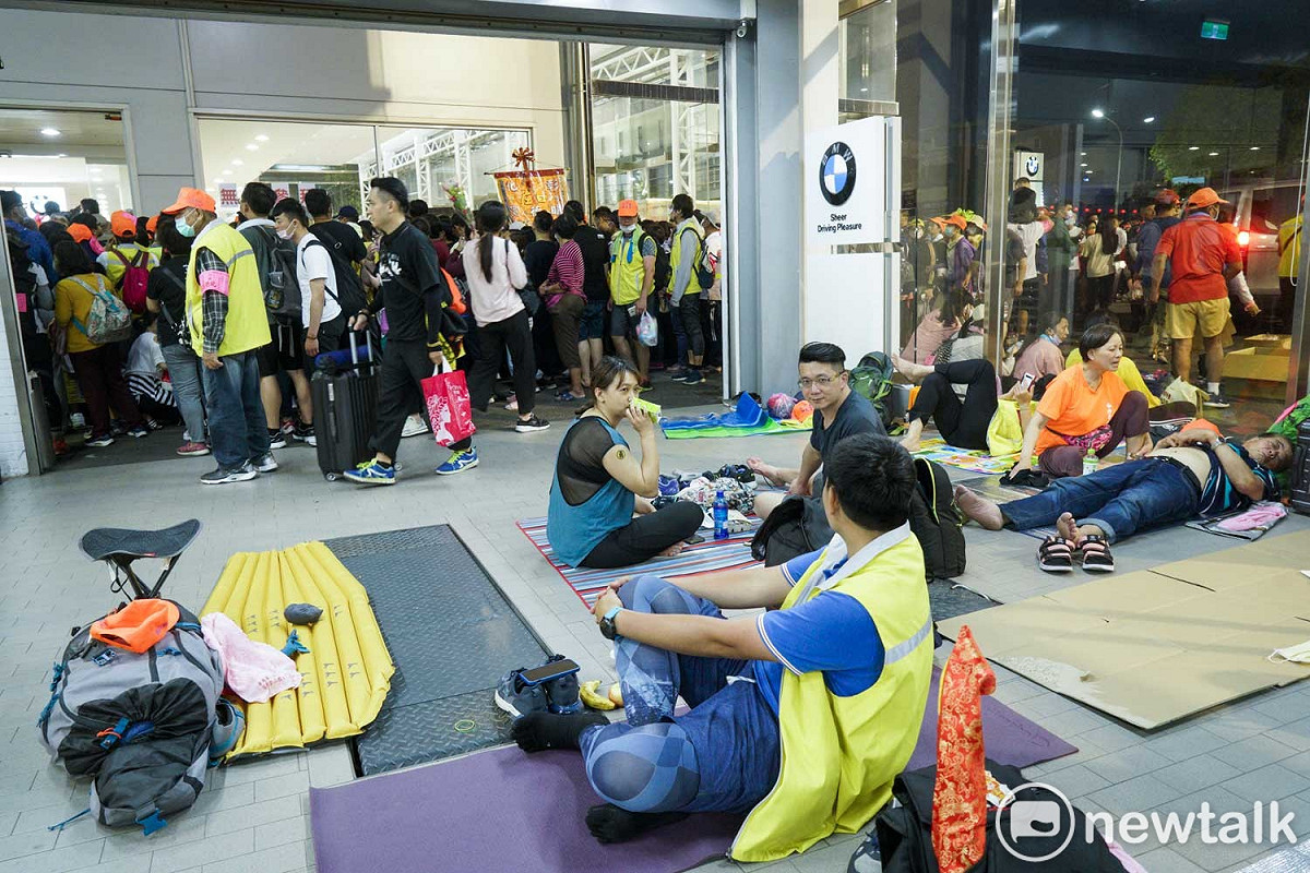 數百位進香客在BMW花壇維修中心內打地鋪休息，緊鄰維修中心的展示間，正是『粉紅超跑』白沙屯媽祖駐駕所在。 圖：張良一/攝
