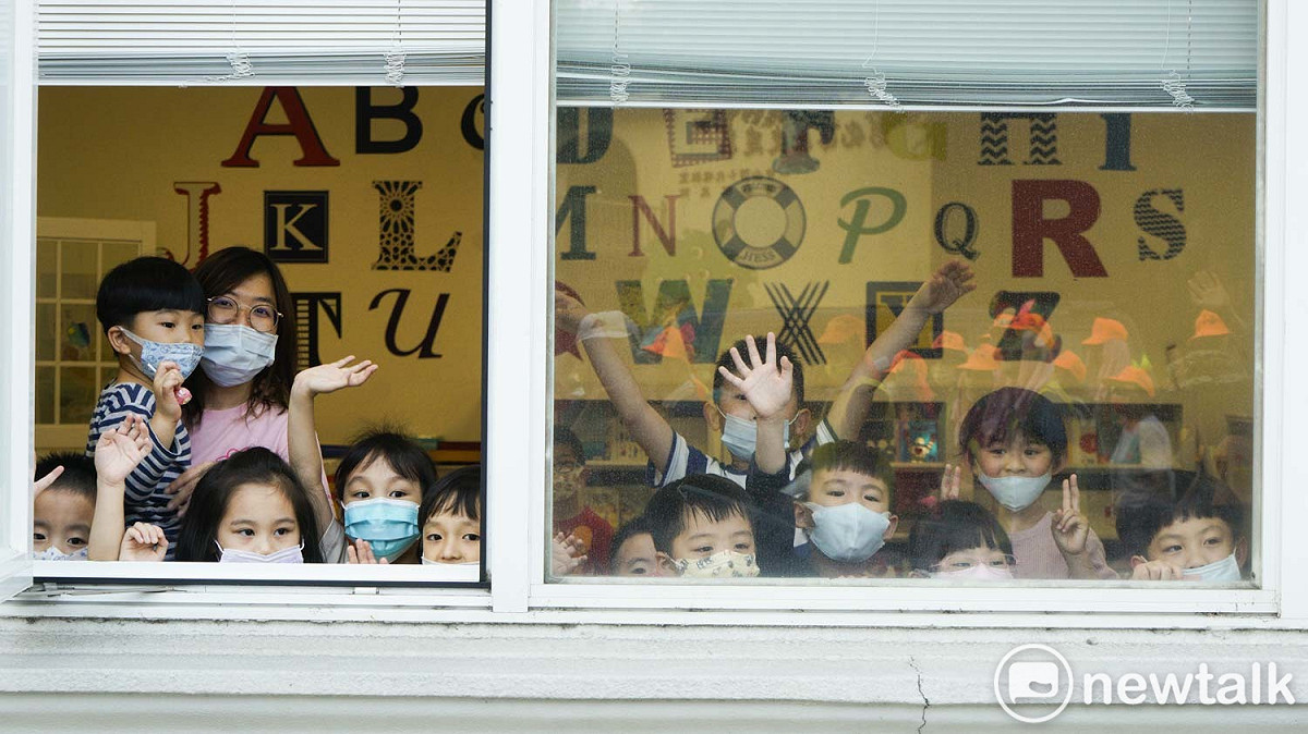 彰化市中山路上一家幼兒園的小朋友們站在窗口向白沙屯媽祖的香燈腳們揮手加油。 圖：張良一/攝