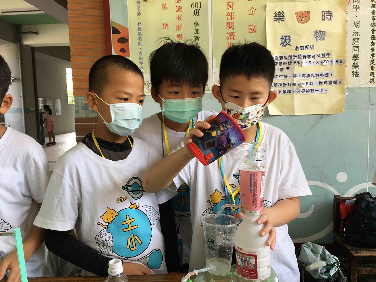 土城國小李紹誠(右)介紹利用連通管水流動來計時。 圖：新北市教育局提供