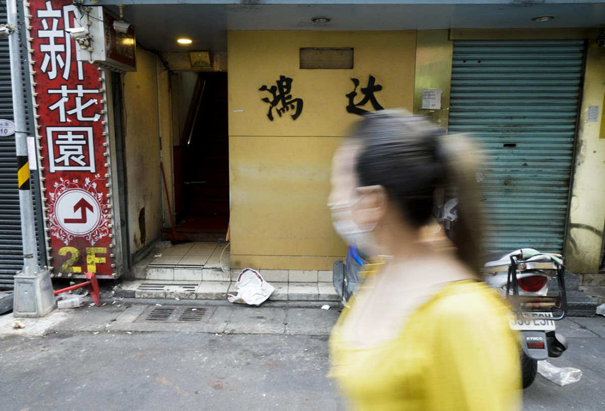 北市萬華區三水街的鴻達清茶館傳出武漢肺炎案例後，鴻達清茶館已拉下鐵門停止營業，一位民眾快速經過鴻達店門口。 圖：張良一/攝