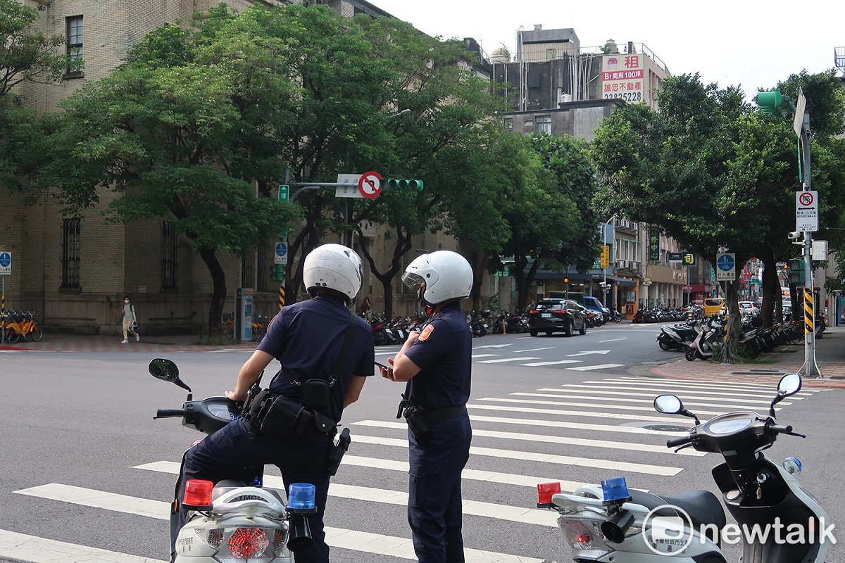 總統府旁寶慶路、博愛路口交通號誌因停電故障，直行、橫行車輛都放慢速度通過，兩名員警站在路口討論 圖：林朝億/攝
