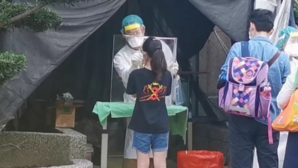 家長帶著剛接到的子女在醫院外排隊接受採檢。 圖：林昀真／翻攝