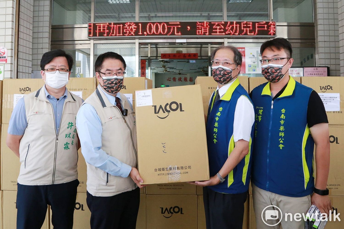 為守護市民健康、支持基層藥局，台南市政府今（16）日率先支援10萬片口罩給社區藥局，由黃偉哲撥交口罩給藥師公會理事長吳振名。 圖：黃博郎／攝